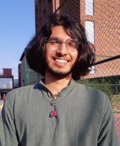 Mukund Maithani, smiling, face lit by the sun, on the Ashoka campus