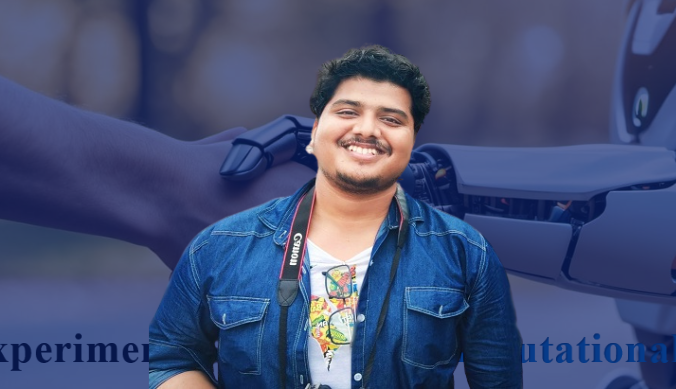 Smiling man in denim shirt with camera strap, robot arm in the blurred background.