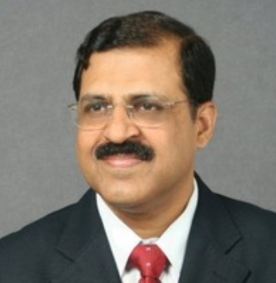 Man in a suit with glasses, mustache, and red tie, smiling against a gray background.