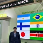 Man standing near a Global Biofuels Alliance display with international flags on a screen.