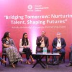 Panel discussion with six speakers seated on stage at Ashoka University's corporate event.