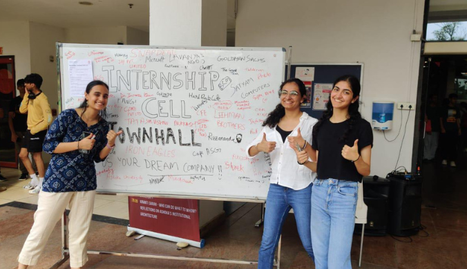 Four people stand in front of a whiteboard with "Internship Cell Townhall" written on it, smiling.