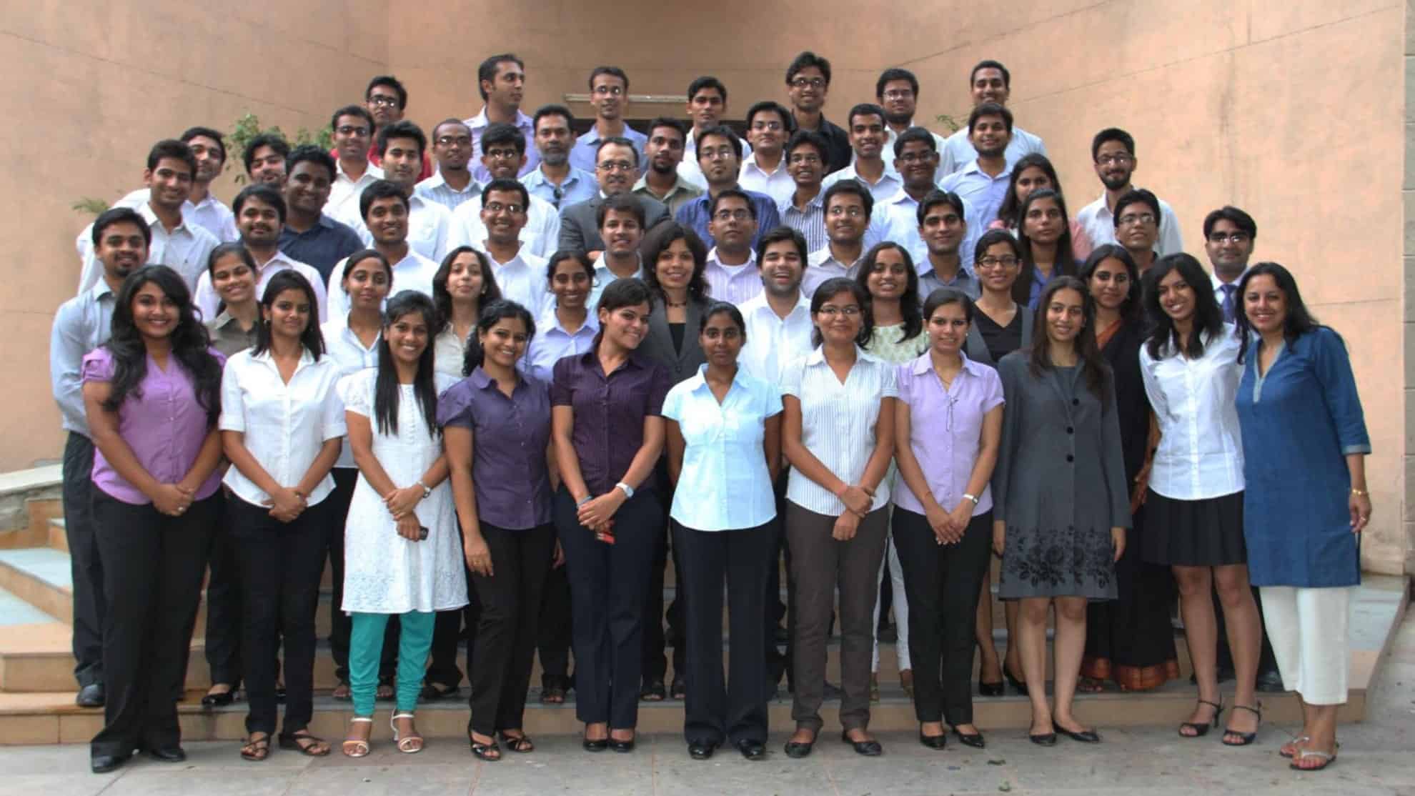 A group of diverse individuals standing on steps, posing together in formal and semi-formal attire.
