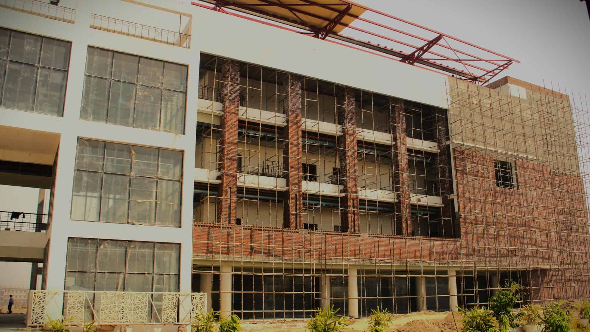 Building under construction with scaffolding, large glass windows, and exposed brickwork.