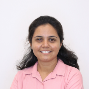 Smiling woman with long dark hair wearing a pink collared shirt against a white background.