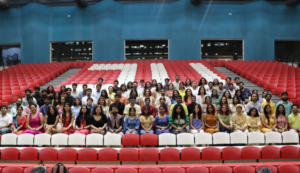 Group of people seated in rows, with red and white stadium seats