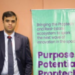 Man in a suit standing next to a banner with text promoting Proptech and real estate innovation.