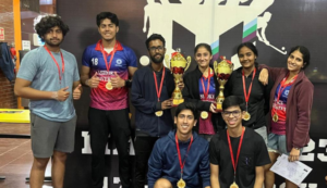 A group of smiling young adults with medals and trophies, posing in front of a sports-themed backdrop.