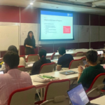 Classroom with a presenter explaining a slide about a statement of purpose to seated students.