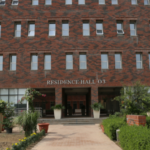 Brick building labeled "Residence Hall 03," with plants and a walkway leading to the entrance.