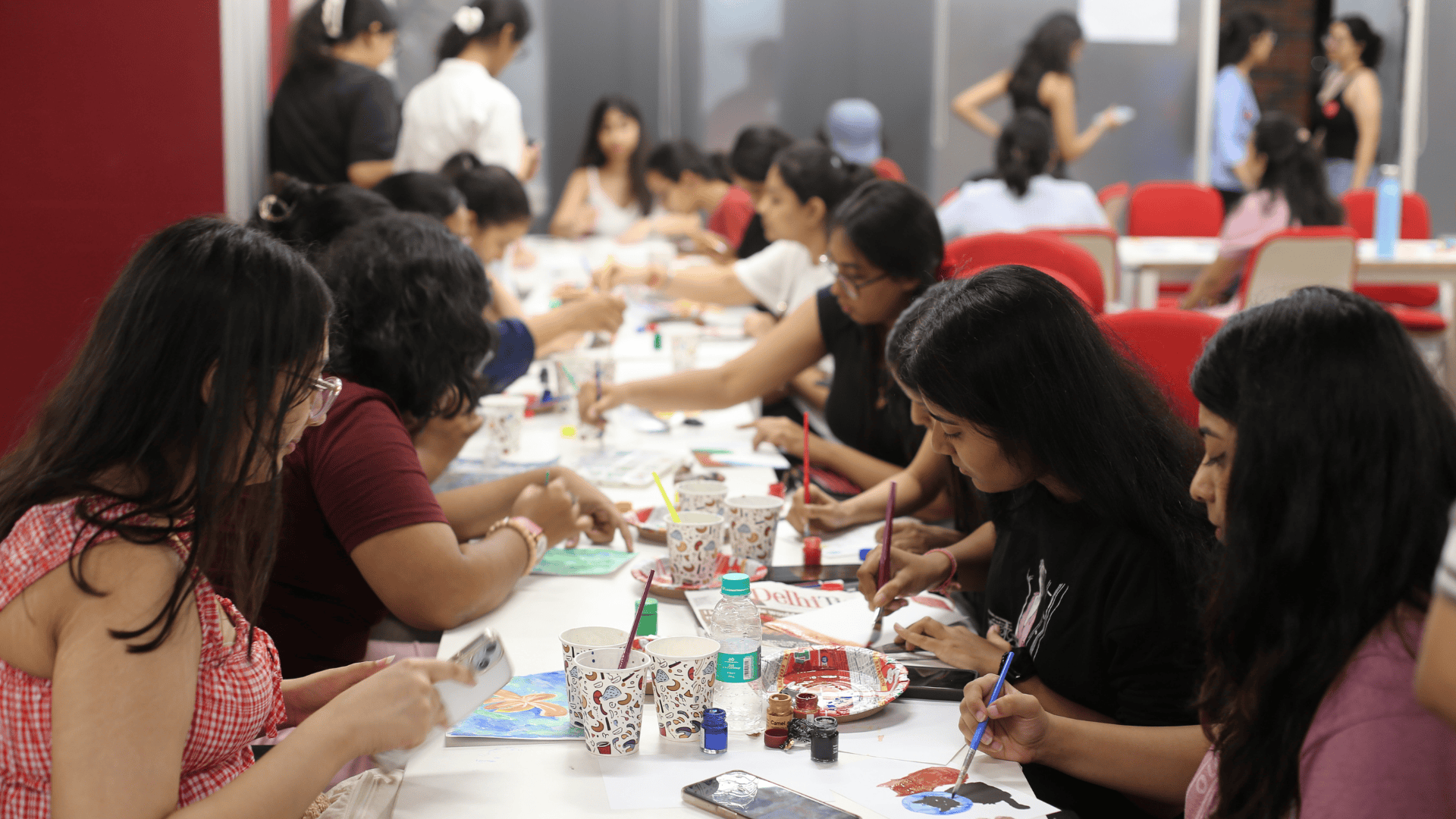 People seated at a table, engaged in painting and crafting, with art supplies scattered around.